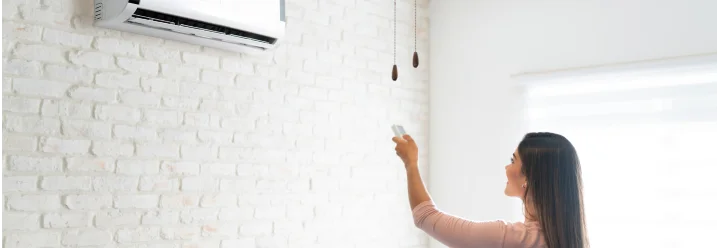 Person bedient Klimaanlage mit Fernbedienung